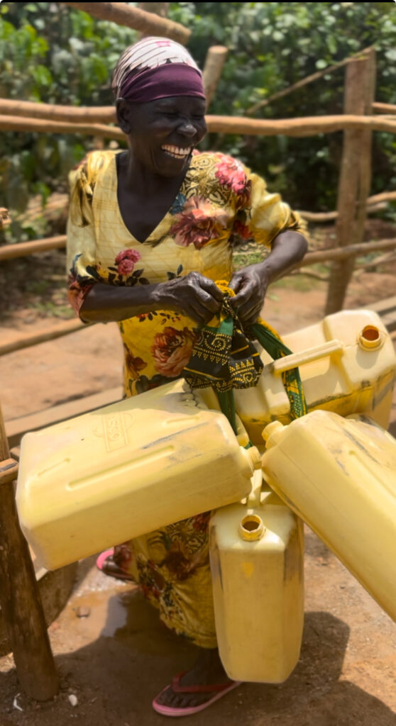 Woman excited to fill her jerry cans with clean water from a new well- Uganda